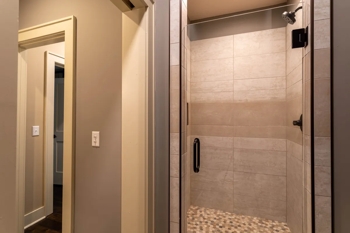 A modern walk-in shower with textured tiles and sleek fixtures is featured in this interior image. The space exudes a spa-like calmness, with ample room for relaxation and rejuvenation after an active day.
