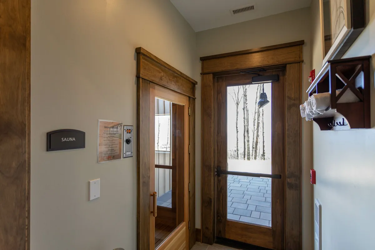 A tranquil, spa-like interior featuring a wooden sauna door, soft lighting, and inviting seating—creating an atmosphere of peace and rejuvenation. It conveys a sense of cozy comfort and relaxation.