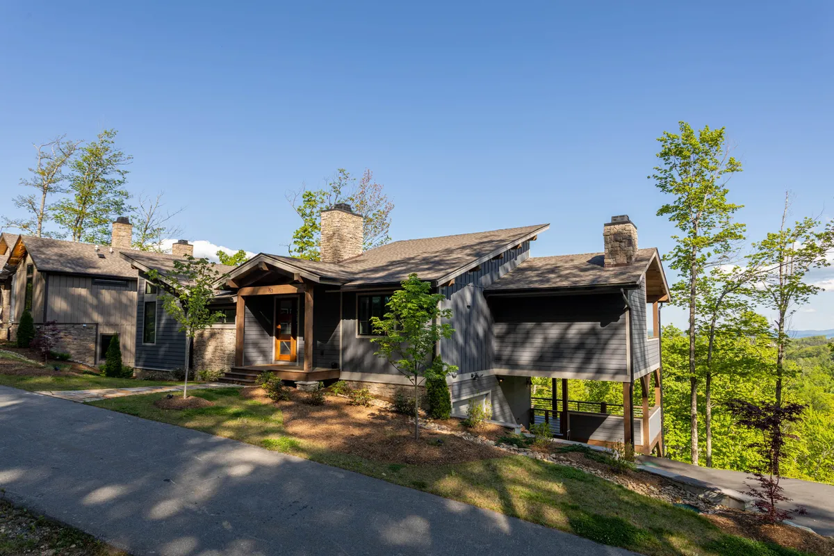 This exterior image showcases the modern architecture of the home, surrounded by lush greenery with a clear pathway leading to the entrance. The scene conveys openness, accessibility, and the natural setting, ideal for both human and canine adventurers. The inviting pathway and visible green space hint at plenty of room for pets to explore and play safely.